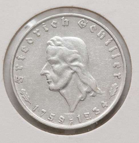 Die Rückseite der Münze zeigt den deutschen Reichsadler in einer klaren, hoheitlichen Darstellung. Über dem Adler ist im Halbkreis „Deutsches Reich“ zu lesen, während darunter der Nennwert „2 Reichsmark“ in eleganter Frakturschrift aufgebracht ist. Flankiert wird der Text von kleinen Eichenblättern, die das klassische Design abrunden.