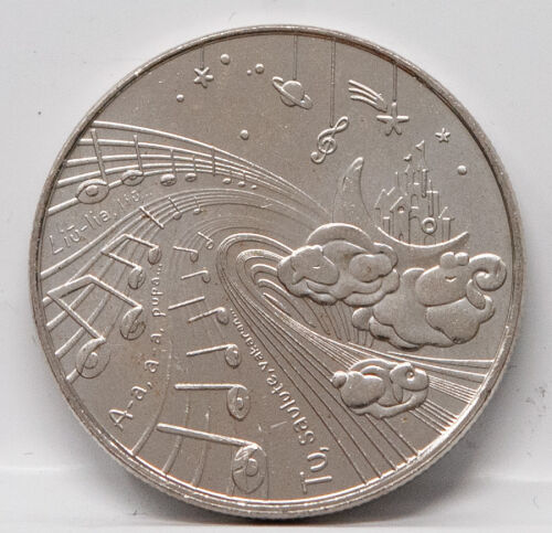 Nahaufnahme der Motivseite: Ein traumhaftes Ensemble aus Notenlinien, Sternen, Planeten und litauischen Textfragmenten. Zu sehen sind schlafende Hasen und ein Schloss auf dem Mond. Die Prägung besticht durch ihre feinen Linien und moderne Ästhetik.